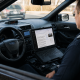 Police officer using laptop inside patrol car