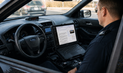 Police officer using laptop inside patrol car