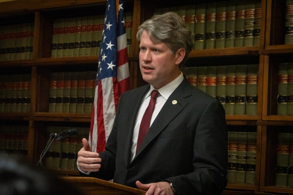 Man speaking at podium with American flag