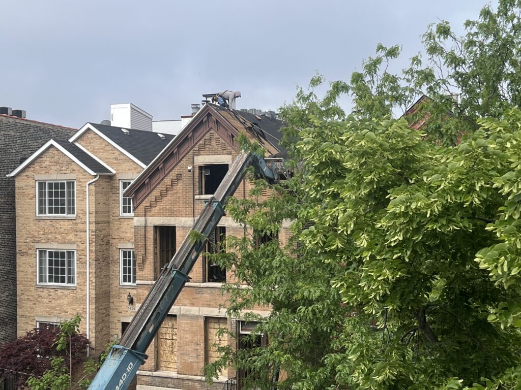 Crane lifting materials onto brick house roof