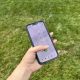 Hand holding smartphone dialing 911 outdoors