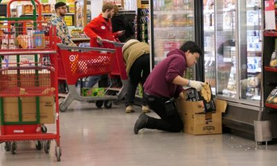 Employee stocking freezer in grocery store aisle