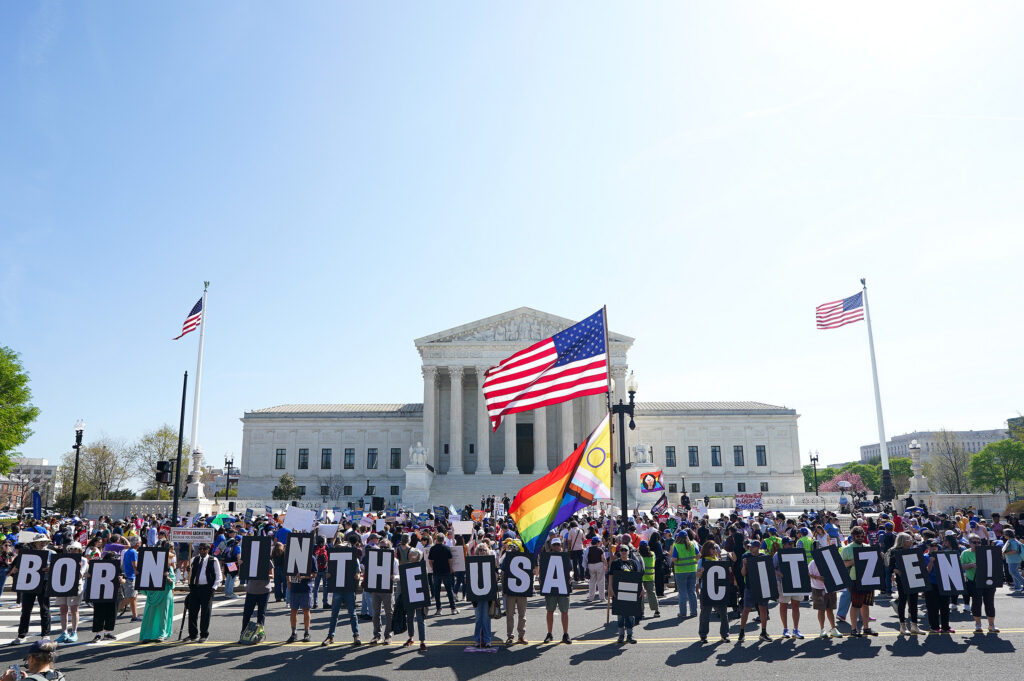 Protesters outside Supreme Court holding citizenship signs
