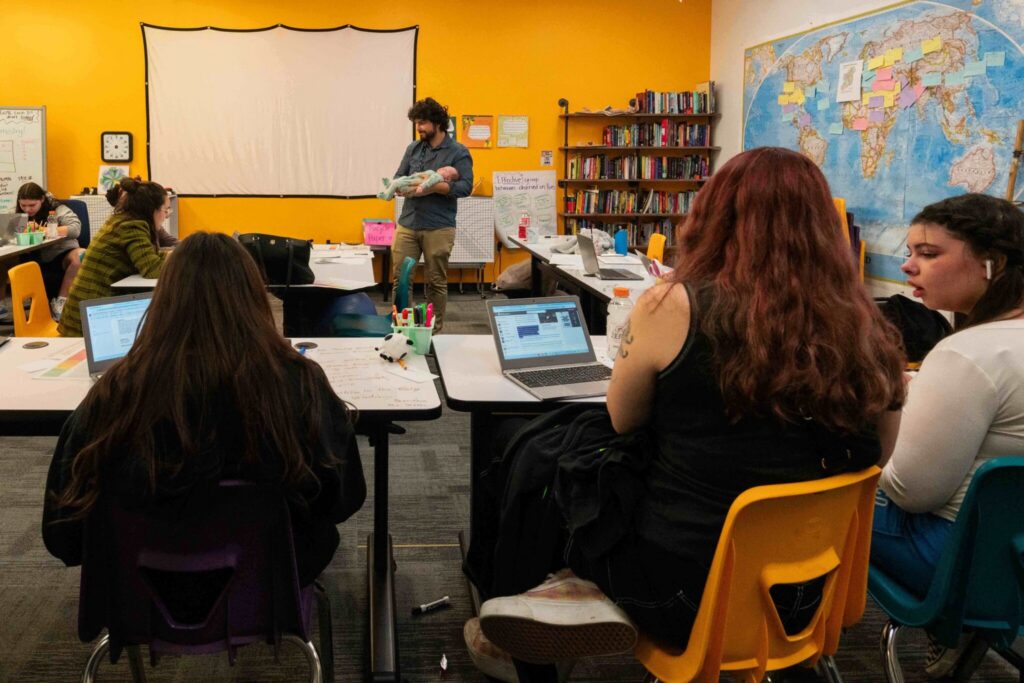 Teacher holding baby in classroom with students