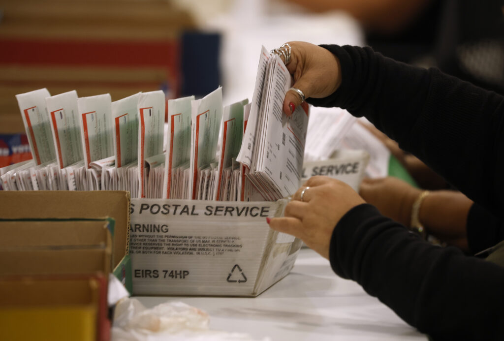 Person sorting mail-in ballots in postal box