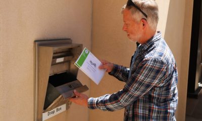 Man placing envelope into outdoor drop box