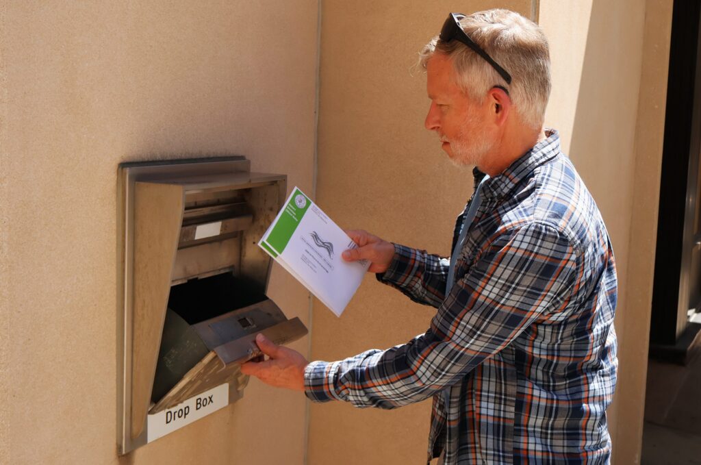 Man placing envelope into outdoor drop box