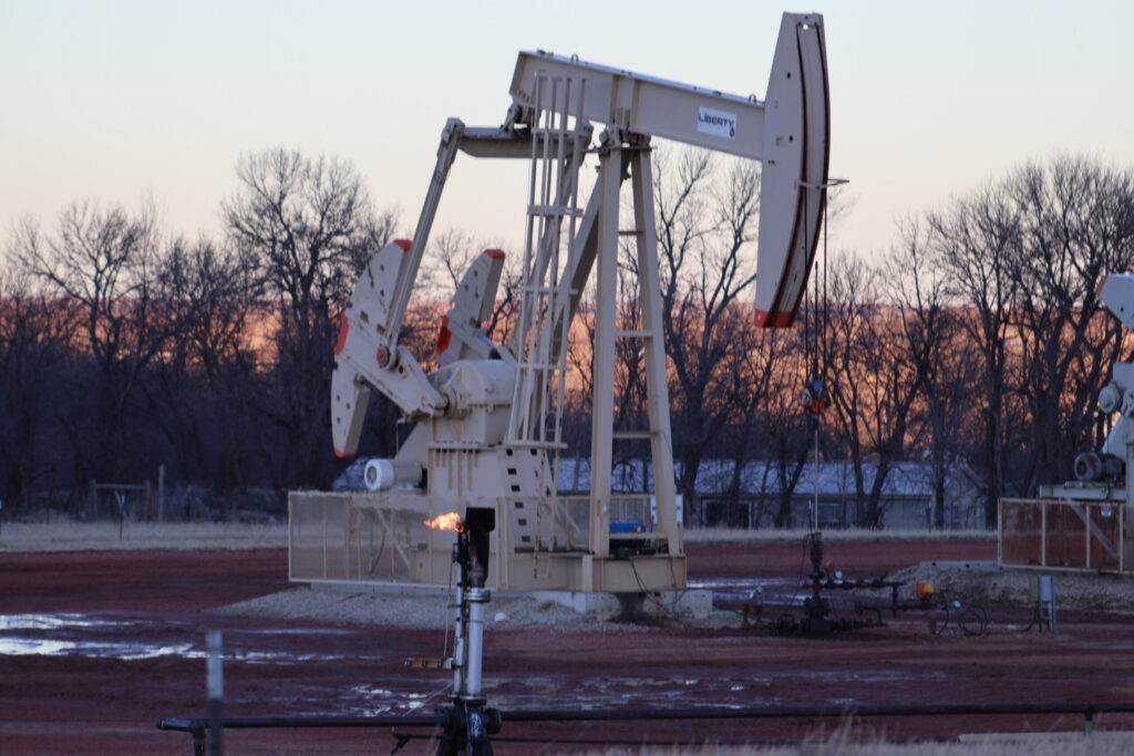 Oil pumpjack operating at dusk in rural field