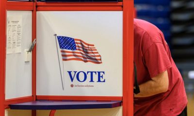 Person voting at booth with American flag