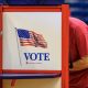 Person voting at booth with American flag