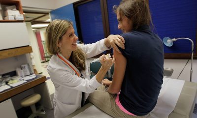 Doctor administering vaccine to teenage girl in clinic