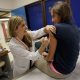 Doctor administering vaccine to teenage girl in clinic