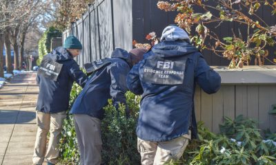 FBI agents in jackets examining a bush near a fence, highlighting crime investigation efforts. — FBI crime report 2025