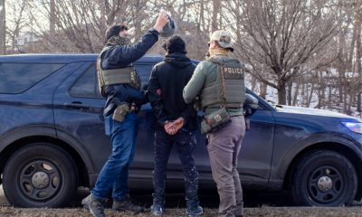 Law enforcement officers in tactical gear apprehending an individual near a police ve — sanctuary policies ICE enforcement