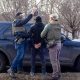Law enforcement officers in tactical gear apprehending an individual near a police ve — sanctuary policies ICE enforcement