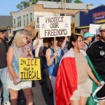 Protesters march holding signs against ICE and immigration enforcement, with a Me — federal law enforcement grants lawsuit