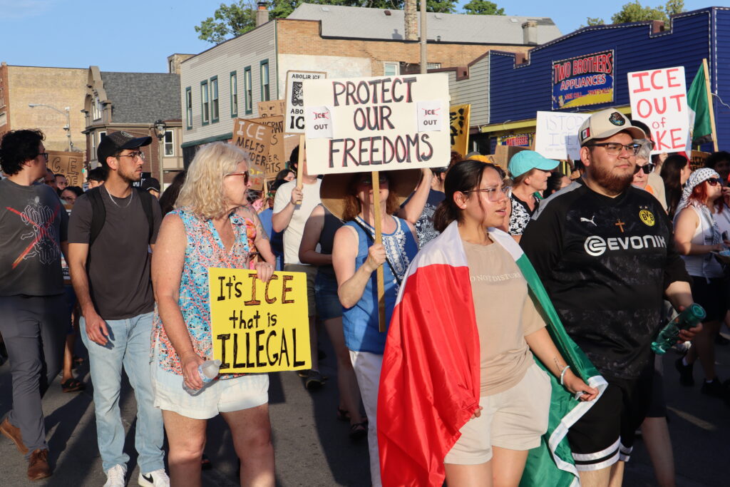 Protesters march holding signs against ICE and immigration enforcement, with a Me — federal law enforcement grants lawsuit