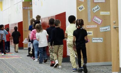 Children walking in a school hallway, passing by colorful educational posters and lock — federal education funding waivers