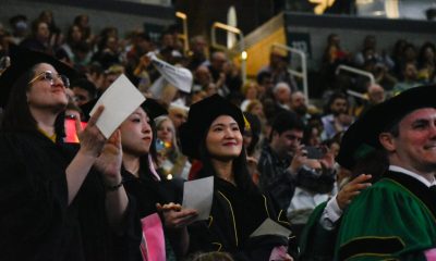 Graduates in caps and gowns celebrating at a commencement ceremony, with a crowd in the backg — DHS H-1B visa fee proposal