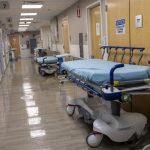 Empty hospital hallway with stretchers and medical equipment, reflecting a quiet — private equity healthcare acquisitions
