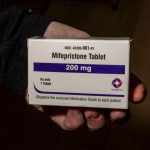 A hand holding a box of mifepristone tablets, labeled 200 mg, with instructions for patients. — mifepristone lawsuit texas