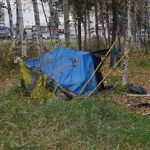 A makeshift tent in a grassy area surrounded by trees, highlighting homelessnes — trump administration homelessness grants