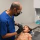 A pediatric dentist examines a young girl in a dental office, highlighting immigrant children healthcare challenges.