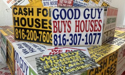 Colorful signs advertising cash home buying services, stacked together, with phone n — Real Estate Wholesaling Regulations