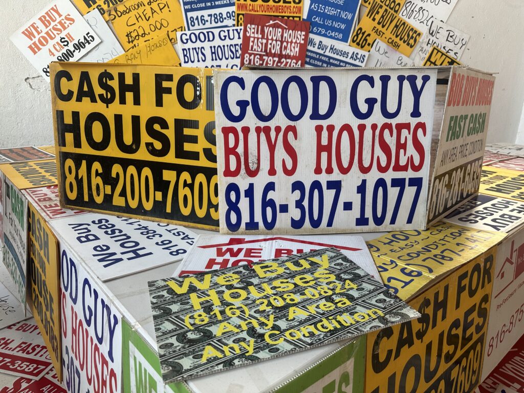 Colorful signs advertising cash home buying services, stacked together, with phone n — Real Estate Wholesaling Regulations