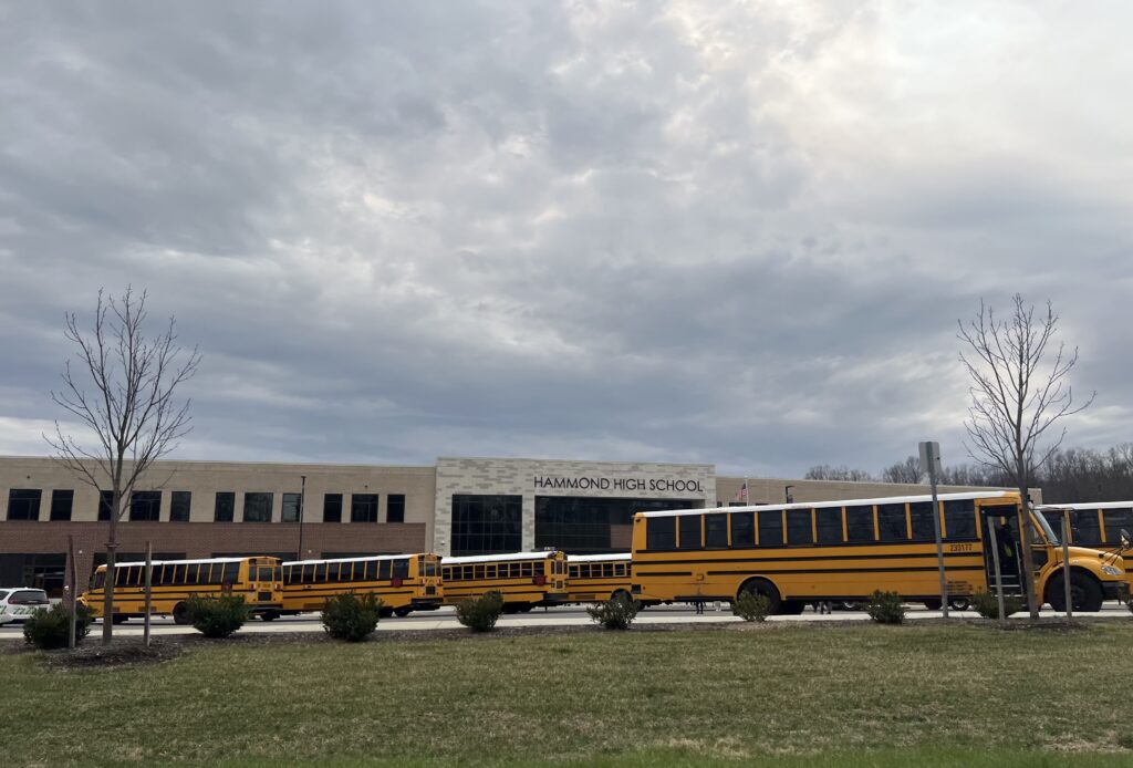 Hammond High School with yellow school buses parked outside under a cloudy sky. — Violent Victimization at School 2024