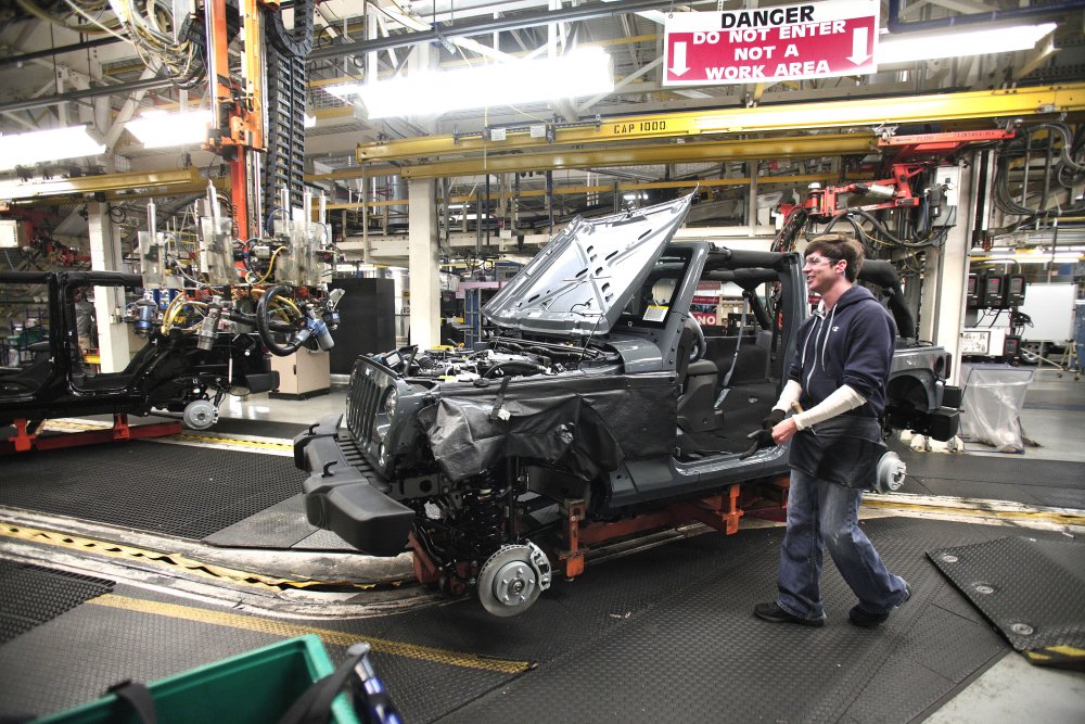 An auto worker in a manufacturing facility assembling a vehicle amid machinery and equip — Trump Canada trade war midterms