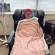A smiling woman in a hospital chair wrapped in a blanket, undergoing treatm — cancer vaccine clinical trial North Carolina