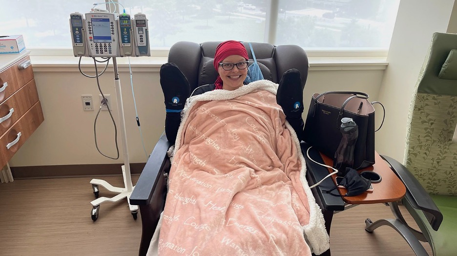 A smiling woman in a hospital chair wrapped in a blanket, undergoing treatm — cancer vaccine clinical trial North Carolina