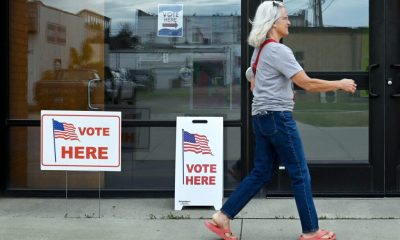 A woman walks past polling signs that say 'Vote Here' outside a voting location. — can trump send troops to polling places
