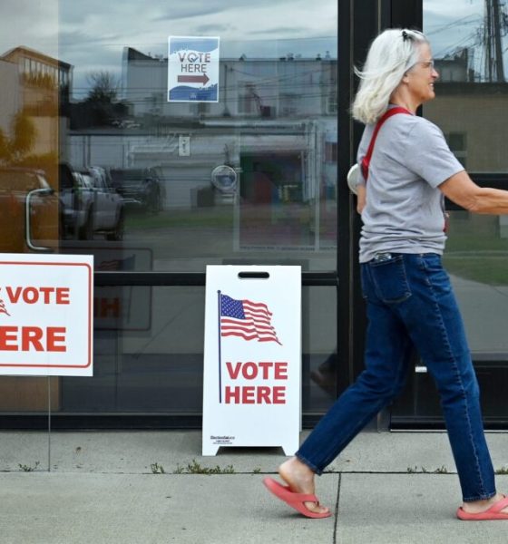 A woman walks past polling signs that say 'Vote Here' outside a voting location. — can trump send troops to polling places