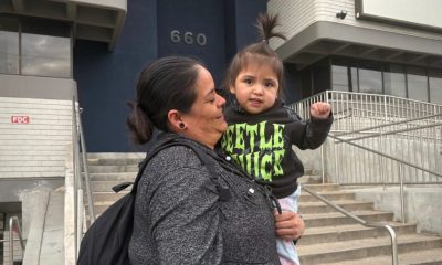 A woman holds a young child outside a building, both smiling, with the number 660 visib — Trump Public Charge Rule Lawsuit