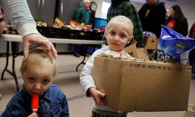 Two children at a food distribution event, one holding a box of snacks and the other with a popsicle. — us poverty rate