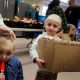 Two children at a food distribution event, one holding a box of snacks and the other with a popsicle. — us poverty rate