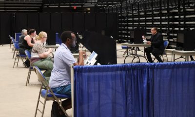 Voters seated at individual booths in a spacious arena, casting their ballots durin — Noncitizen Voter Purge Supreme Court