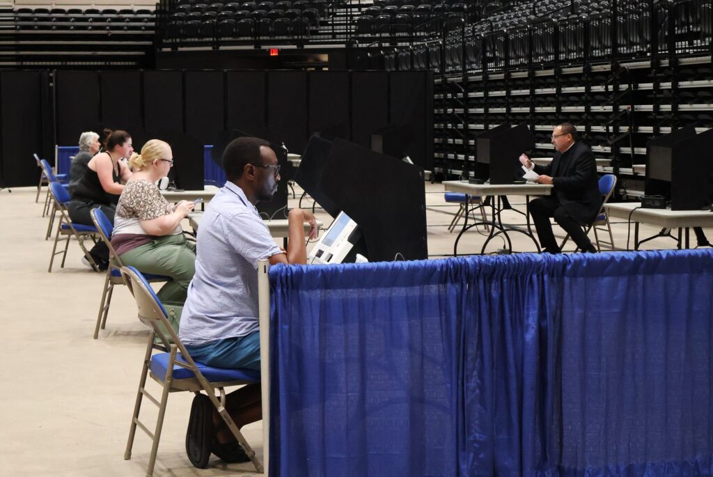 Voters seated at individual booths in a spacious arena, casting their ballots durin — Noncitizen Voter Purge Supreme Court