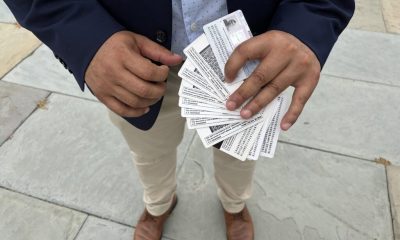A person holding multiple identification cards, standing on a stone surface, advo — Temporary Protected Status El Salvador