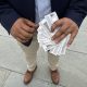 A person holding multiple identification cards, standing on a stone surface, advo — Temporary Protected Status El Salvador