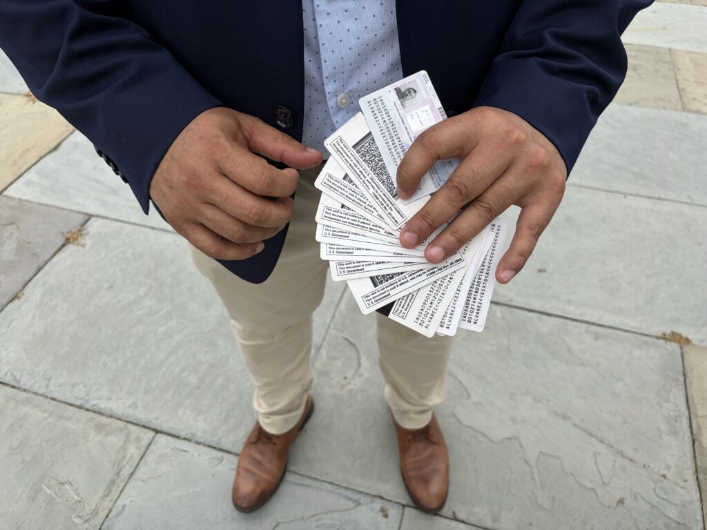 A person holding multiple identification cards, standing on a stone surface, advo — Temporary Protected Status El Salvador