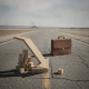 A symbolic representation of US job growth June showing a downward trend with wooden blocks and a briefcase on a cracked r…