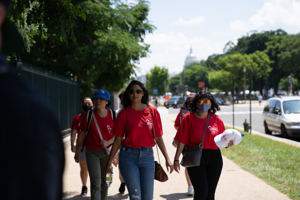 AAPI women reproductive healthcare advocates walk together along a tree-lined Washington, D.C., sidewalk.
