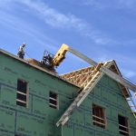 Construction worker on a building site with wooden framing and green insulation pa — Housing Ballot Measures November 2024