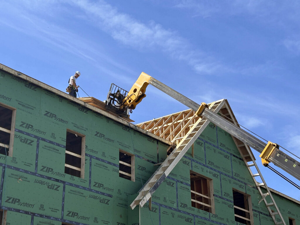 Construction worker on a building site with wooden framing and green insulation pa — Housing Ballot Measures November 2024