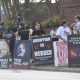 Protesters hold anti-abortion signs along a sidewalk, including posters showing fetal — pregnancy criminal charges report