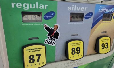 Gas pump displaying fuel prices with a sticker featuring a thumbs-up gesture and text referenc — States Suspending Gas Tax