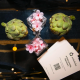 Artichokes, pink flowers, and an Artichoke Credit Union business card arranged on a reflective table.